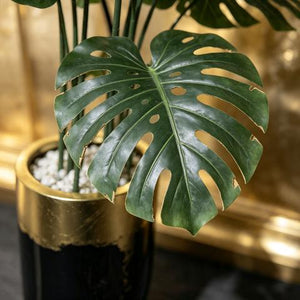 Monstera deliciosa artificiel en pot noir brillant – Liseré doré & galets blancs