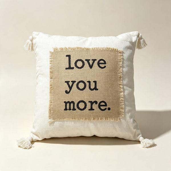 Coussin décoratif écru avec patch en jute et message “Love You More”