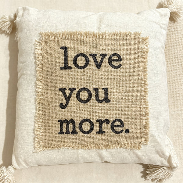 Coussin décoratif écru avec patch en jute et message “Love You More”